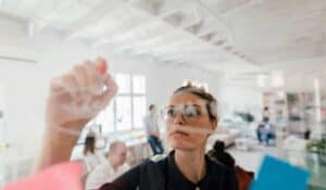 business women drawing on board with coworkers in background