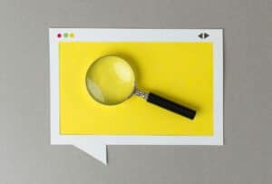 magnifying glass in front of a yellow speech bubble