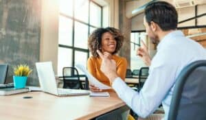 Business women and man sitting in meeting room smiling while discussing