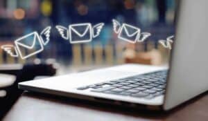 Animated envelopes with wings flying over laptop keyboard