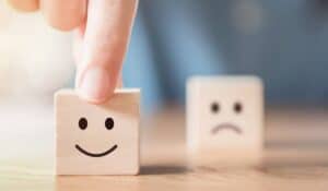 two wooden blocks one with a happy face one with a sad face