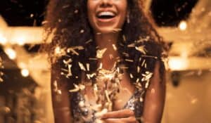 woman wearing a party dress and holding a sparkler while laughing