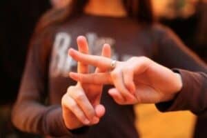 girl crossing her fingers in the shape of a hashtag